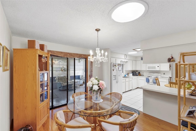 dining area featuring a textured ceiling, an inviting chandelier, and light wood-style flooring