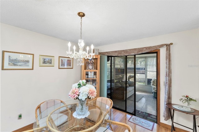 dining space featuring a textured ceiling, light wood-style floors, baseboards, and a chandelier