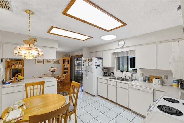 kitchen with white appliances, light tile patterned floors, visible vents, a sink, and light countertops