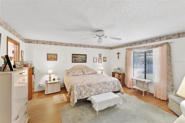 bedroom featuring baseboards, ceiling fan, a textured ceiling, and light wood-style floors