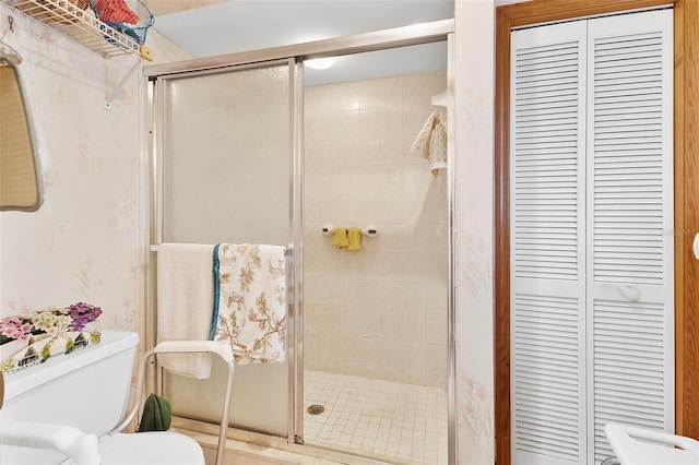 full bathroom featuring a closet, toilet, a shower stall, and wallpapered walls