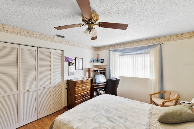 bedroom featuring visible vents, ceiling fan, wood finished floors, a closet, and a textured ceiling