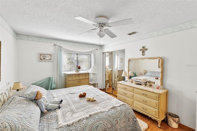 bedroom with visible vents, a textured ceiling, a closet, light wood finished floors, and ceiling fan