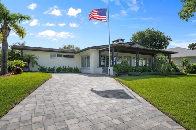 rear view of property with a lawn, a porch, and decorative driveway