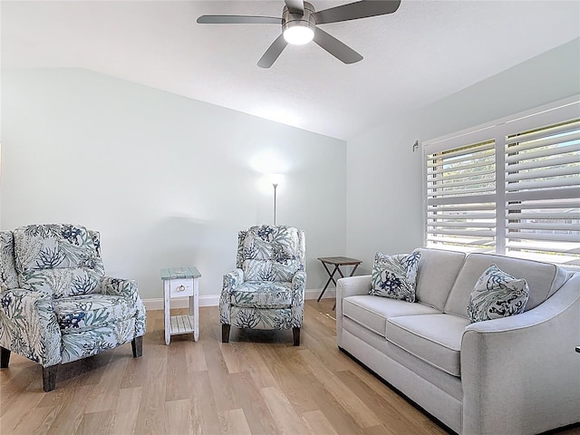 living area featuring lofted ceiling, light wood-style flooring, baseboards, and ceiling fan