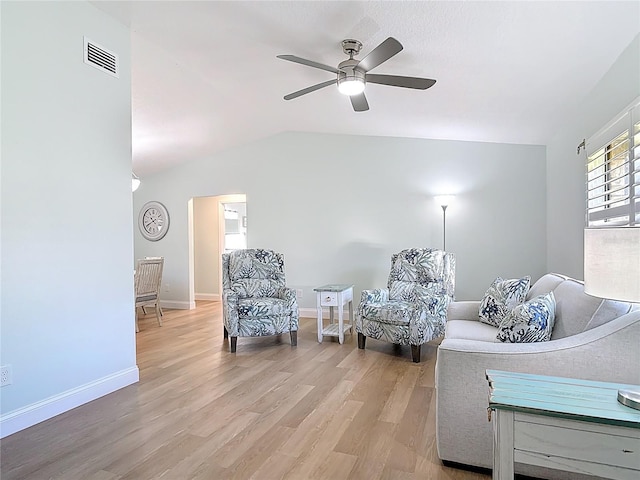 living area with visible vents, a ceiling fan, light wood finished floors, baseboards, and vaulted ceiling