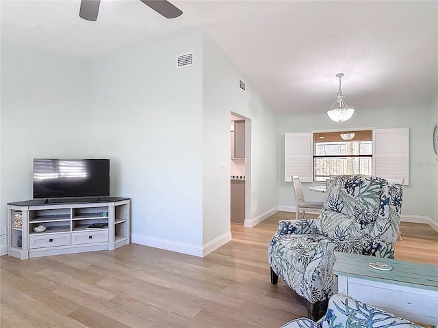 living area featuring vaulted ceiling, light wood-style flooring, visible vents, and baseboards