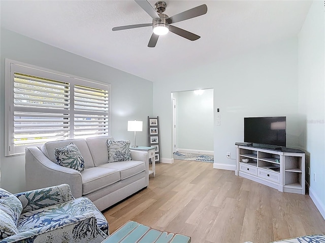 living area with baseboards, light wood-style floors, ceiling fan, and vaulted ceiling