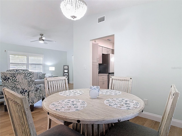 dining space with visible vents, baseboards, ceiling fan with notable chandelier, and light wood finished floors