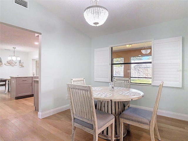 dining room with a notable chandelier, light wood-style floors, visible vents, and baseboards