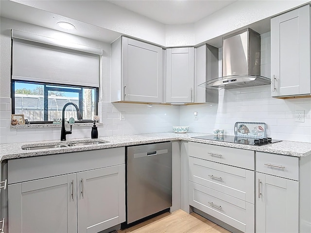 kitchen with black electric stovetop, wall chimney range hood, gray cabinets, stainless steel dishwasher, and a sink