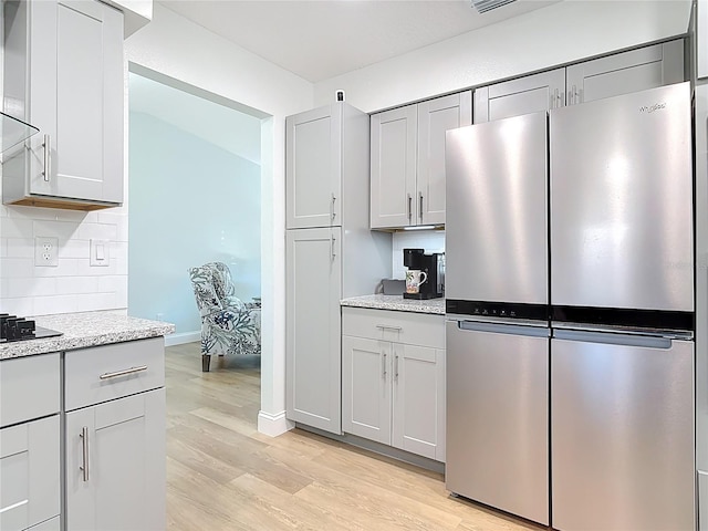 kitchen with light wood finished floors, tasteful backsplash, gray cabinets, and freestanding refrigerator