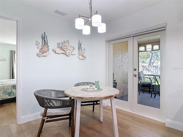 dining room with light wood finished floors, visible vents, french doors, and baseboards