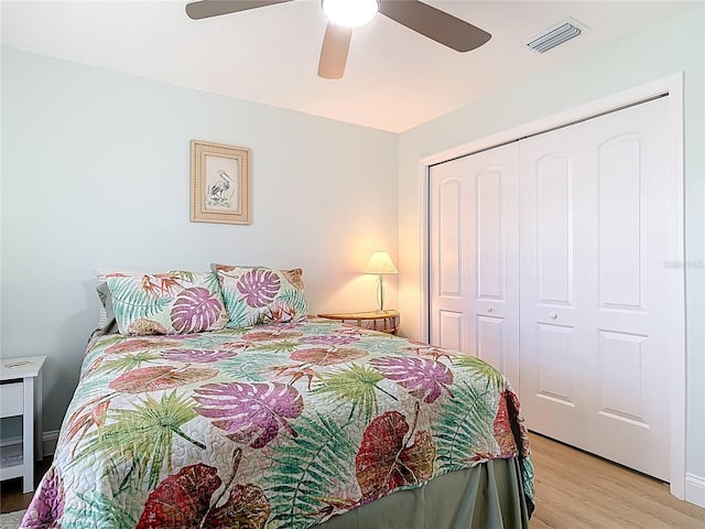 bedroom featuring light wood-style flooring, a ceiling fan, visible vents, and a closet