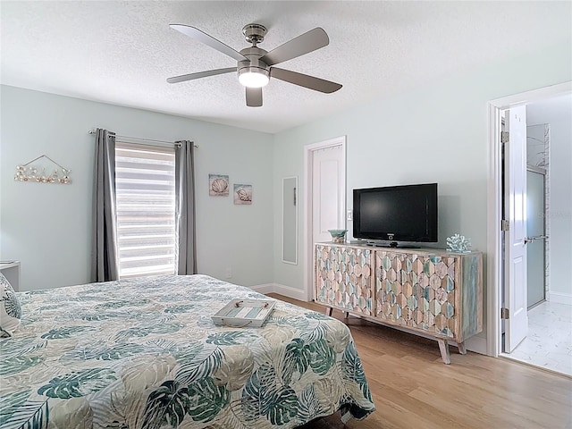 bedroom featuring ceiling fan, baseboards, a textured ceiling, and wood finished floors