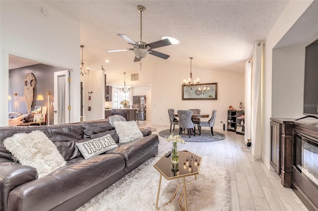 living room featuring ceiling fan with notable chandelier, a textured ceiling, lofted ceiling, and wood finish floors