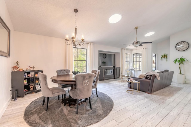 dining room featuring baseboards, light wood finished floors, ceiling fan with notable chandelier, and vaulted ceiling