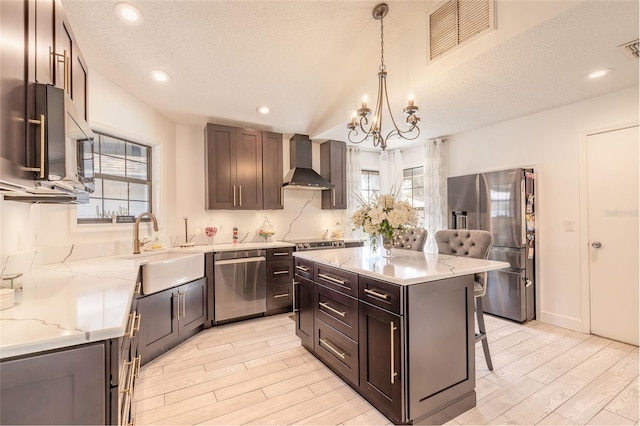 kitchen with visible vents, stainless steel appliances, an inviting chandelier, a breakfast bar area, and wall chimney exhaust hood