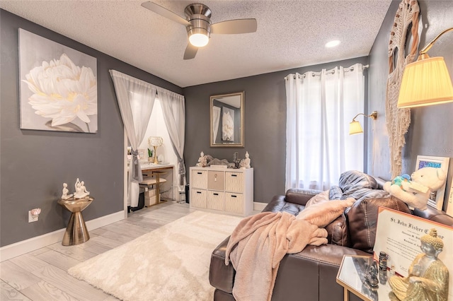 bedroom featuring a ceiling fan, baseboards, light wood finished floors, and a textured ceiling