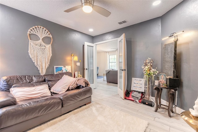 living area with ceiling fan, visible vents, a textured ceiling, and wood finished floors