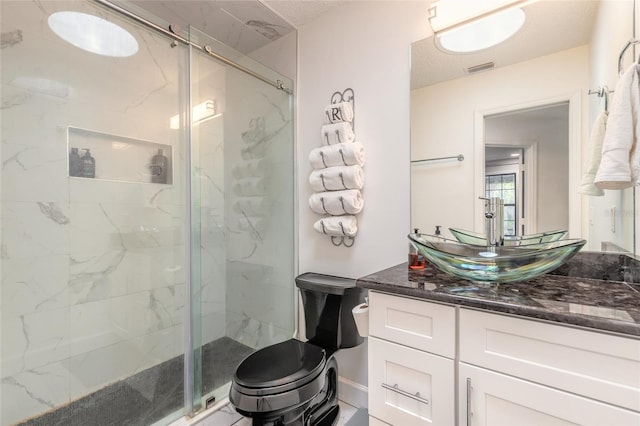 bathroom featuring a marble finish shower, toilet, visible vents, and vanity