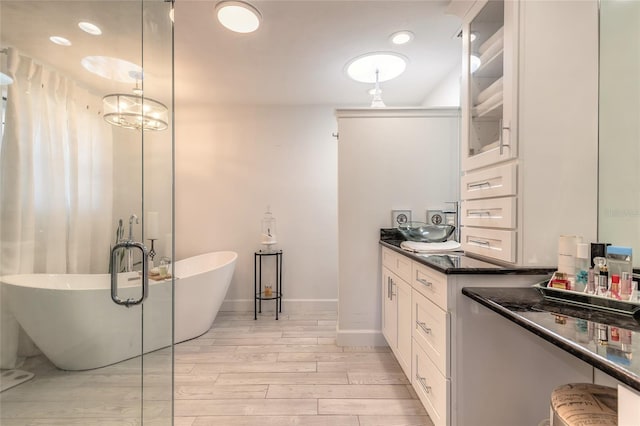 bathroom featuring a freestanding bath, vanity, baseboards, and wood finished floors