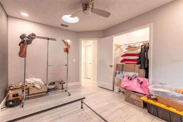 workout room featuring visible vents, baseboards, ceiling fan, wood finished floors, and a textured ceiling