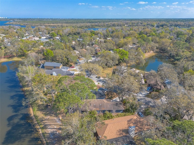 drone / aerial view featuring a wooded view and a water view