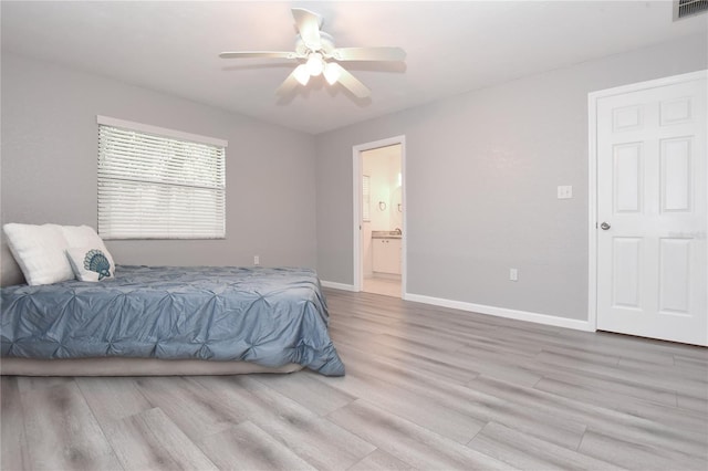 bedroom featuring wood finished floors, baseboards, visible vents, and ensuite bathroom