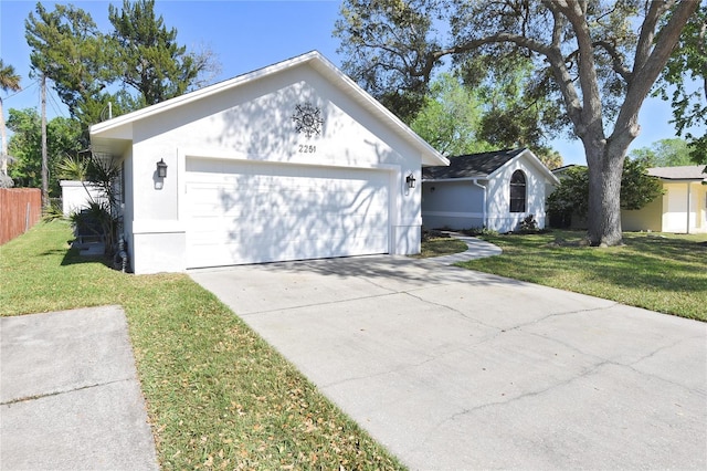 exterior space with a front lawn, concrete driveway, fence, and stucco siding