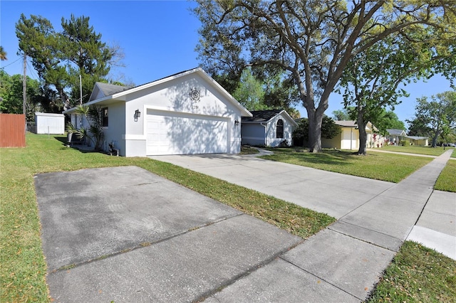 view of side of property featuring stucco siding, a lawn, an attached garage, and fence