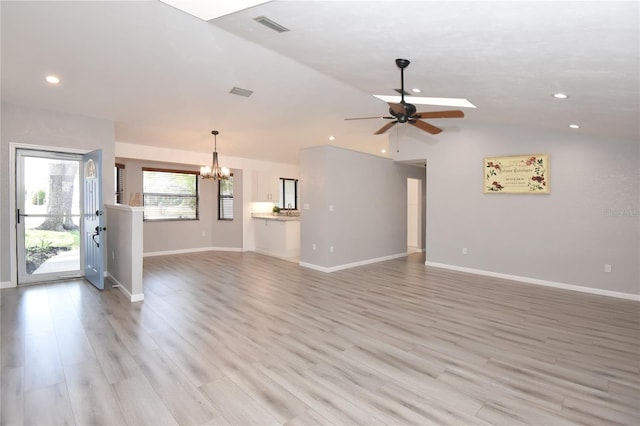 unfurnished living room with visible vents, baseboards, lofted ceiling, light wood-style flooring, and ceiling fan with notable chandelier