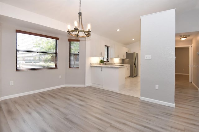 unfurnished living room with baseboards, visible vents, an inviting chandelier, recessed lighting, and light wood-style floors