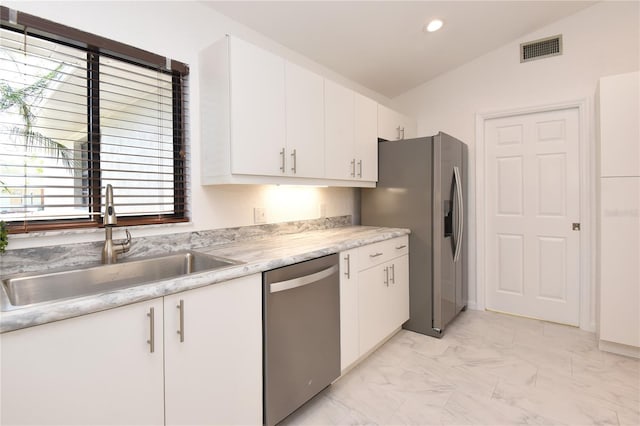 kitchen featuring visible vents, lofted ceiling, a sink, appliances with stainless steel finishes, and marble finish floor