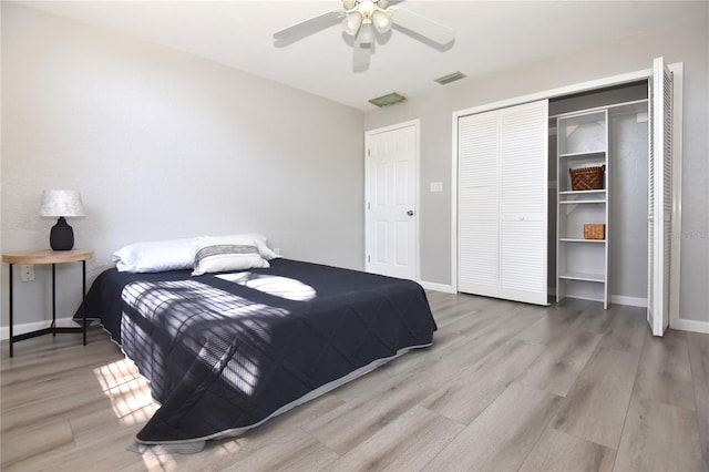 bedroom with wood finished floors, visible vents, a closet, and baseboards