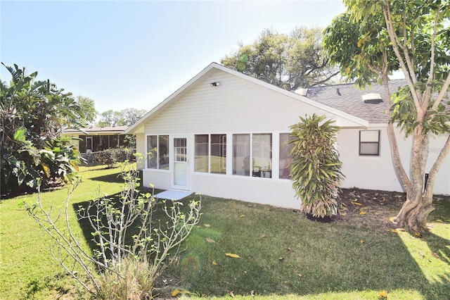 back of property with stucco siding, a lawn, and a sunroom