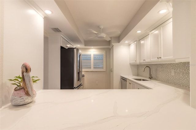 kitchen with light stone counters, white cabinets, appliances with stainless steel finishes, and a sink