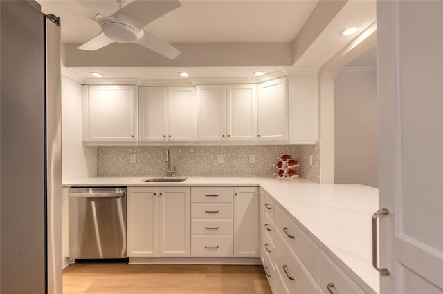 kitchen featuring white cabinetry, light wood-style flooring, a sink, dishwasher, and backsplash