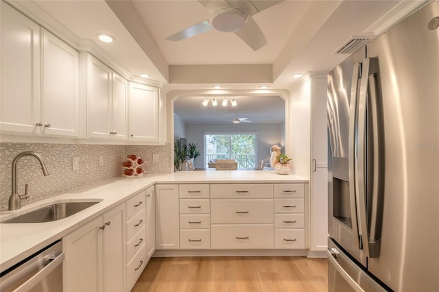 kitchen with light wood-style flooring, a sink, tasteful backsplash, appliances with stainless steel finishes, and white cabinets