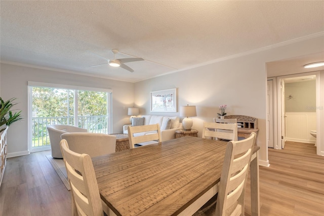 dining area featuring a textured ceiling, crown molding, light wood-type flooring, and ceiling fan