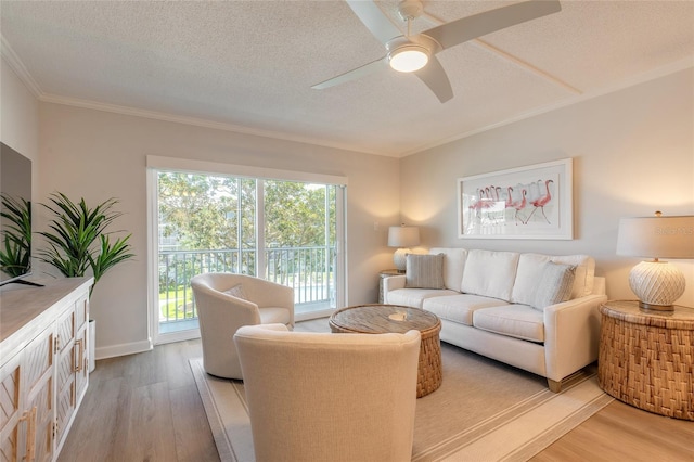 living room featuring light wood-style flooring, a textured ceiling, ceiling fan, and ornamental molding