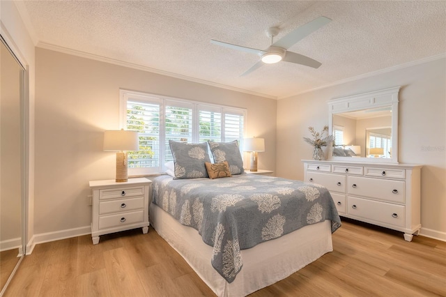 bedroom featuring baseboards, a textured ceiling, crown molding, and light wood-style floors