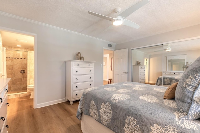 bedroom with a textured ceiling, crown molding, baseboards, and wood finished floors