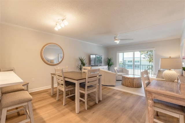 dining room with light wood-style flooring, ornamental molding, a textured ceiling, baseboards, and ceiling fan