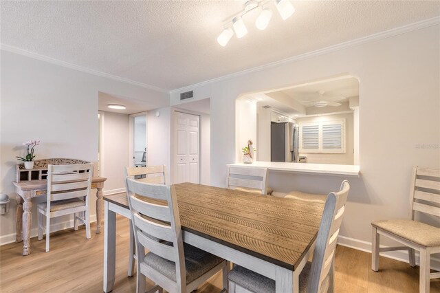 dining area with visible vents, crown molding, baseboards, light wood-style flooring, and a textured ceiling