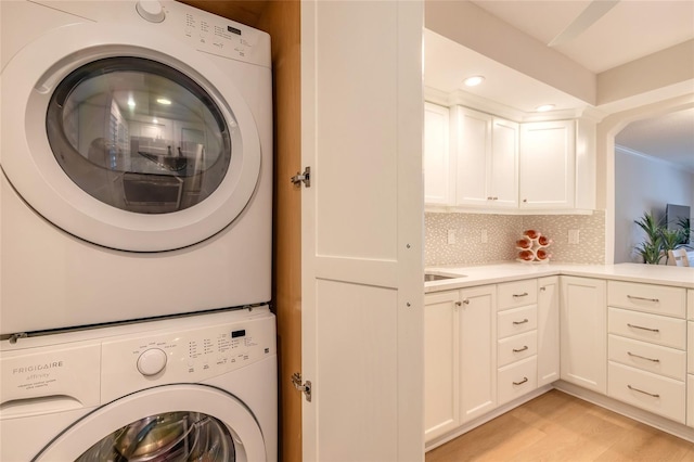 laundry room with recessed lighting, light wood finished floors, laundry area, and stacked washer / dryer