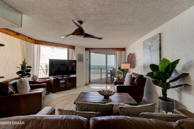 carpeted living area with a textured ceiling and ceiling fan