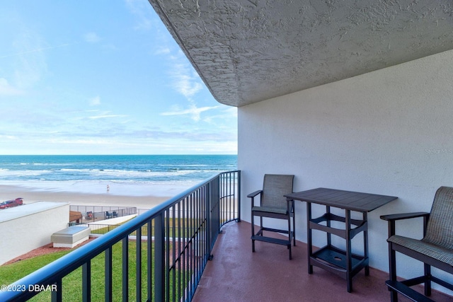 balcony featuring a view of the beach and a water view