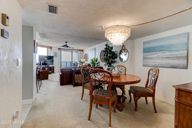 dining area featuring visible vents, light colored carpet, a textured ceiling, and ceiling fan with notable chandelier