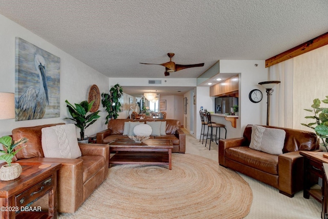 carpeted living room featuring visible vents, a textured ceiling, and ceiling fan